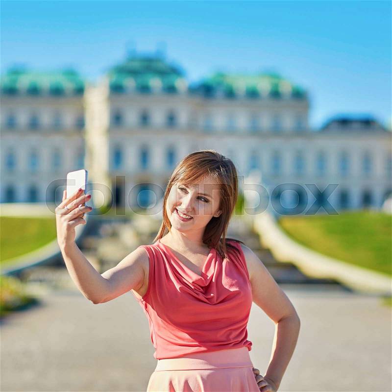 Beautiful young woman walking in Vienna, Austria and taking selfie, stock photo