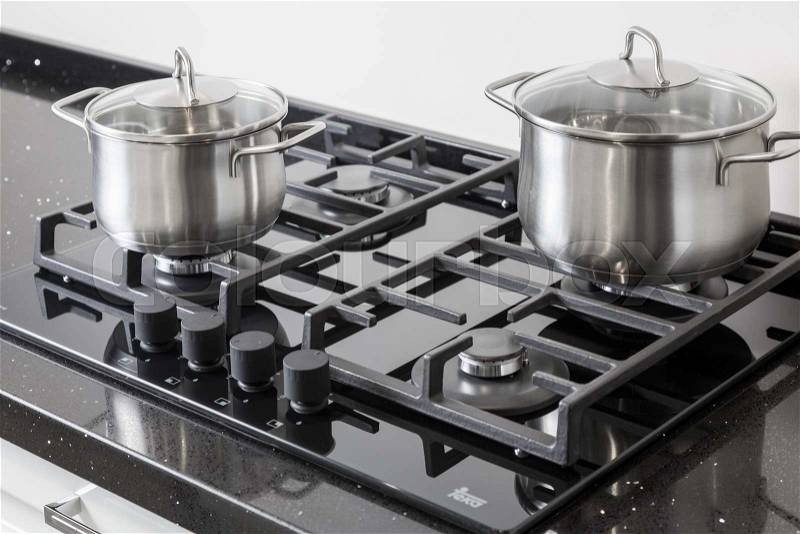 New iron pots on a black gas stove on a kitchen, stock photo
