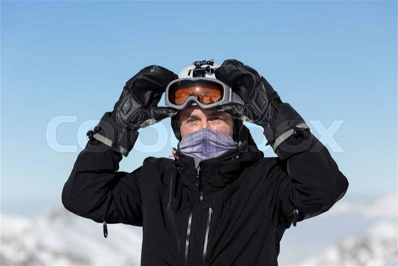 Close-up of male skier wearing ski goggles and ski helmet on a sunny day, stock photo
