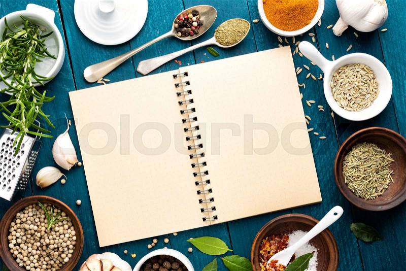 Culinary background and recipe book with various spices on wooden table, stock photo