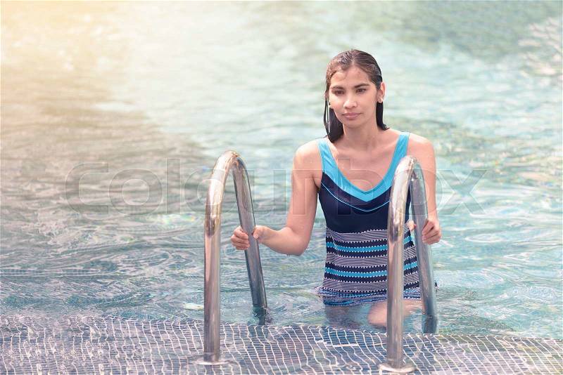 Beautiful Asian girl going out of swimming pool, stock photo