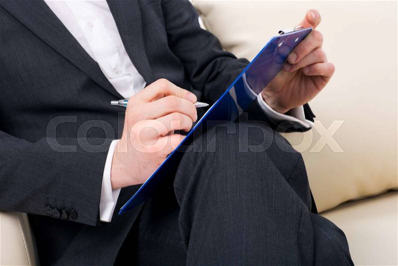 Male psychologist being ready to take notes sitting on the couch, stock photo