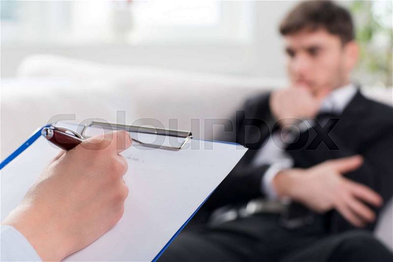 Over the shoulder view, of a business man sit on a couch talking to his psychiatrist, stock photo