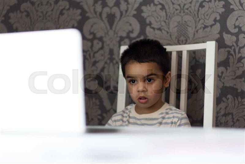 Little boy watching cartoons on his parents laptop, stock photo