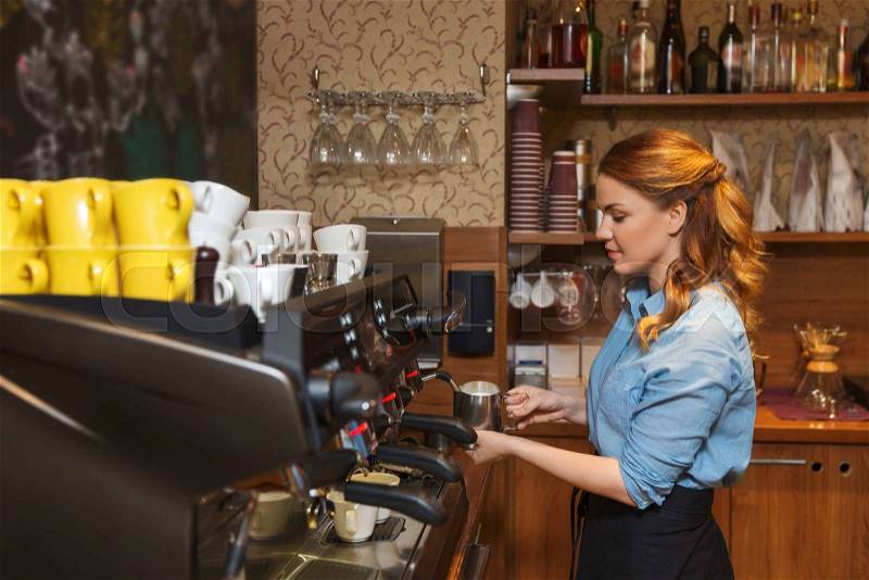 Equipment, coffee shop, people and technology concept - barista woman making coffee by machine at cafe bar or restaurant kitchen, stock photo