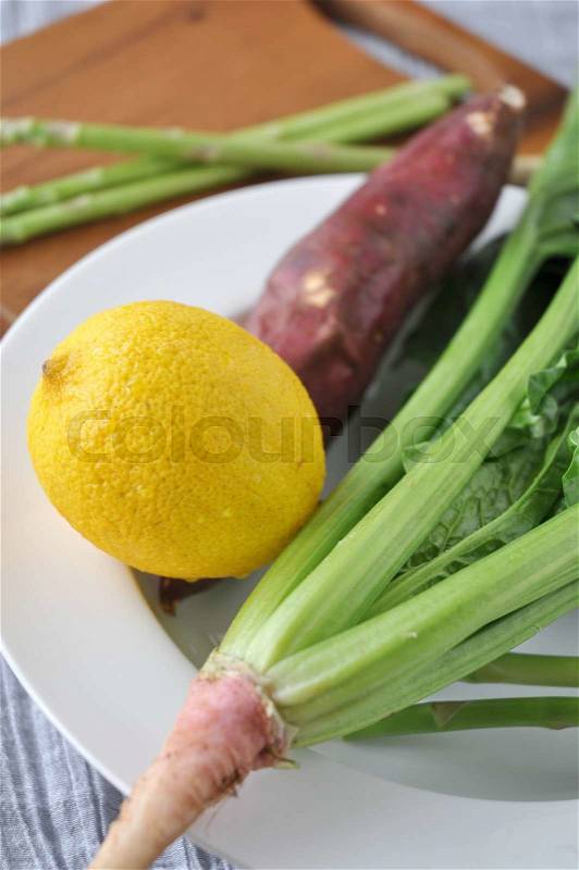 Lemon and fresh veggies on white dish, stock photo