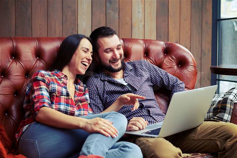 Young couple looking at laptop and laughing, stock photo