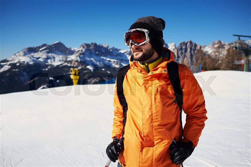 Smiley skier in orange jacket over snow mountains, stock photo