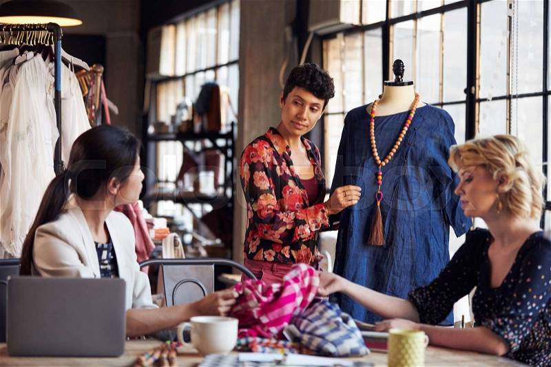 Three Fashion Designers In Meeting Discussing Garment, stock photo