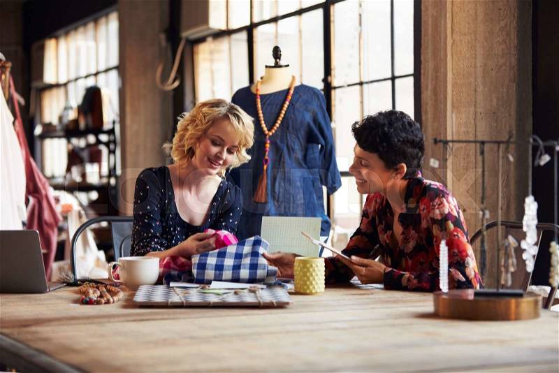 Two Female Fashion Designers In Meeting Discussing Textiles, stock photo