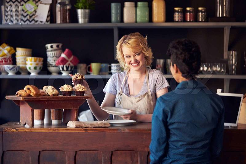 Staff Serving Customer In Busy Coffee Shop, stock photo