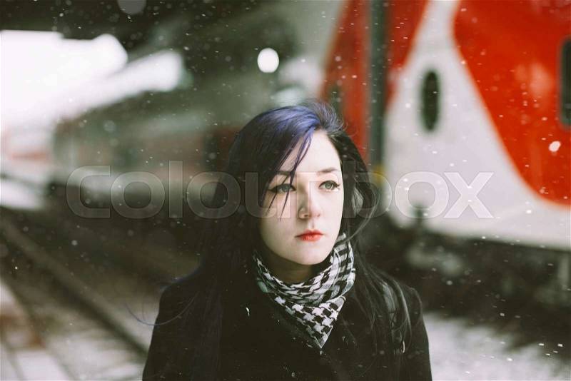Real woman waits at an empty train stop in winter. , stock photo