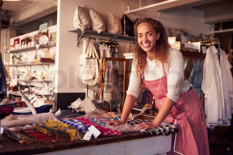 Female Sales Assistant Arranging Textiles In Homeware Store, stock photo
