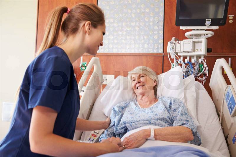 Nurse Talking To Senior Female Patient In Hospital Bed, stock photo