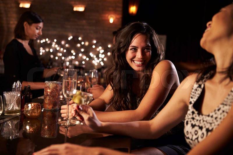 Female Friends Enjoying Night Out At Cocktail Bar, stock photo