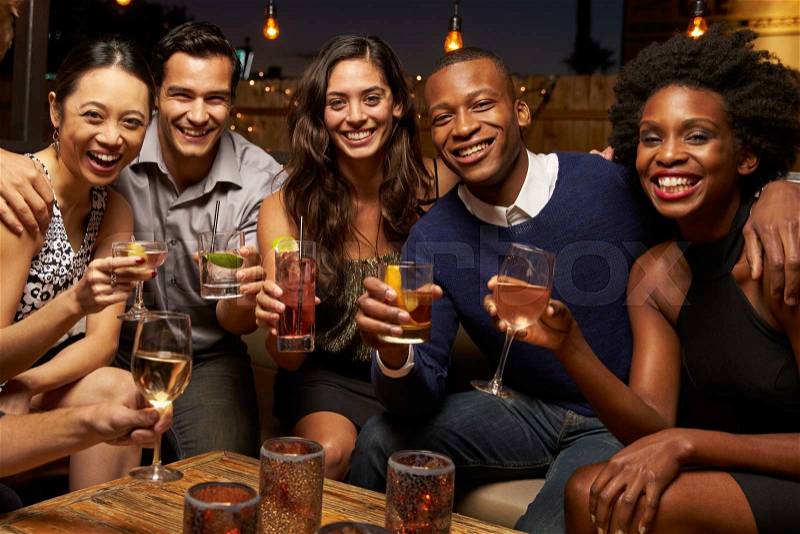 Portrait Of Friends Enjoying Night Out At Rooftop Bar, stock photo