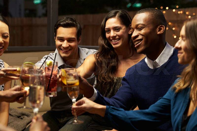 Group Of Friends Enjoying Night Out At Rooftop Bar, stock photo