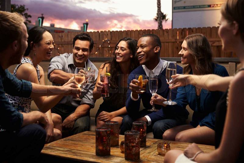 Group Of Friends Enjoying Night Out At Rooftop Bar, stock photo