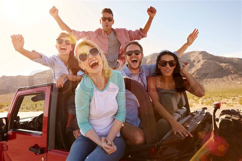 Friends On Road Trip Standing In Convertible Car, stock photo