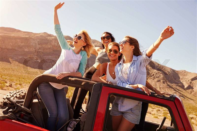Four Female Friends On Road Trip Standing In Convertible Car, stock photo