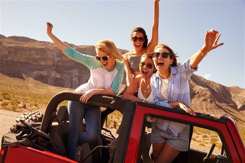 Four Female Friends On Road Trip Standing In Convertible Car, stock photo