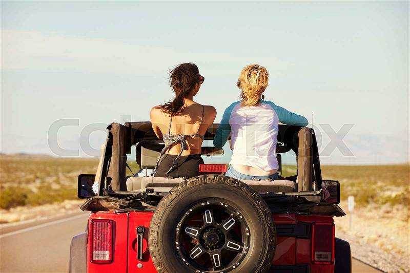 Rear View Of Friends On Road Trip Driving In Convertible Car, stock photo