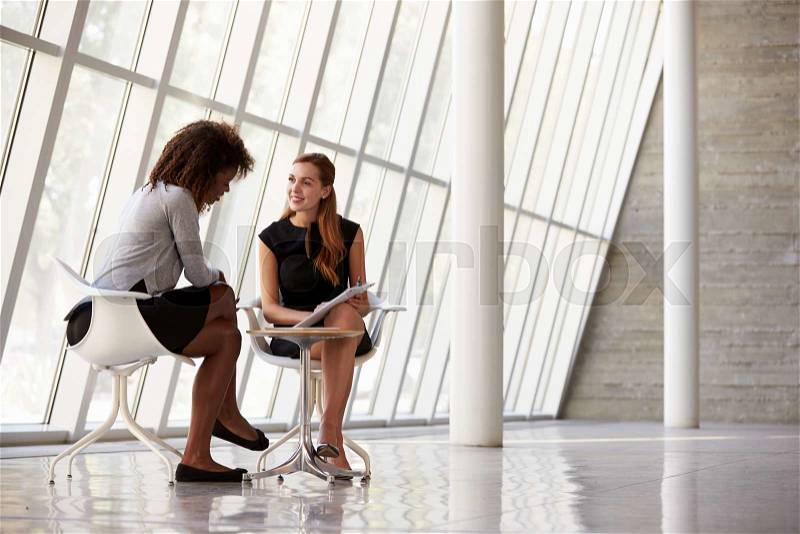 Two Businesswomen Meeting In Reception Of Modern Office, stock photo