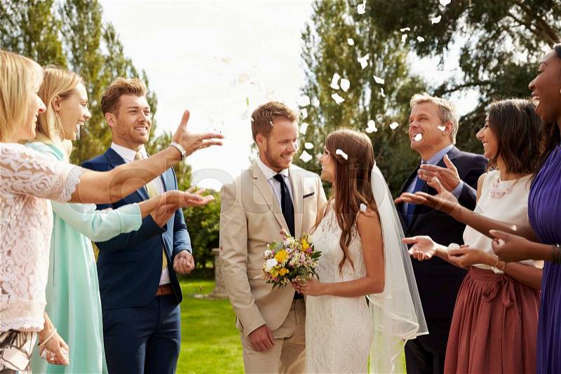 Guests Throwing Confetti Over Bride And Groom At Wedding, stock photo