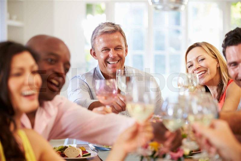 Mature Friends Sitting Around Table At Dinner Party, stock photo