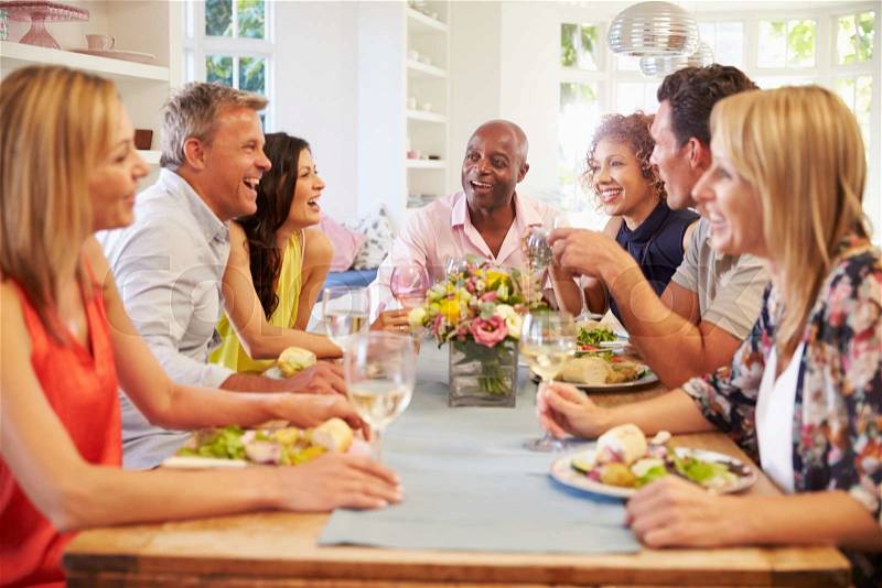 Mature Friends Sitting Around Table At Dinner Party, stock photo