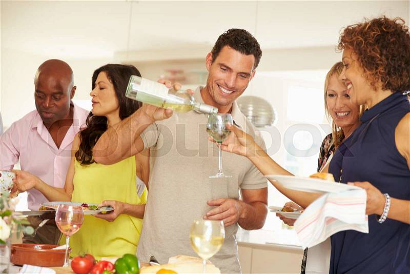 Man Pouring Wine For Guest At Dinner Party, stock photo