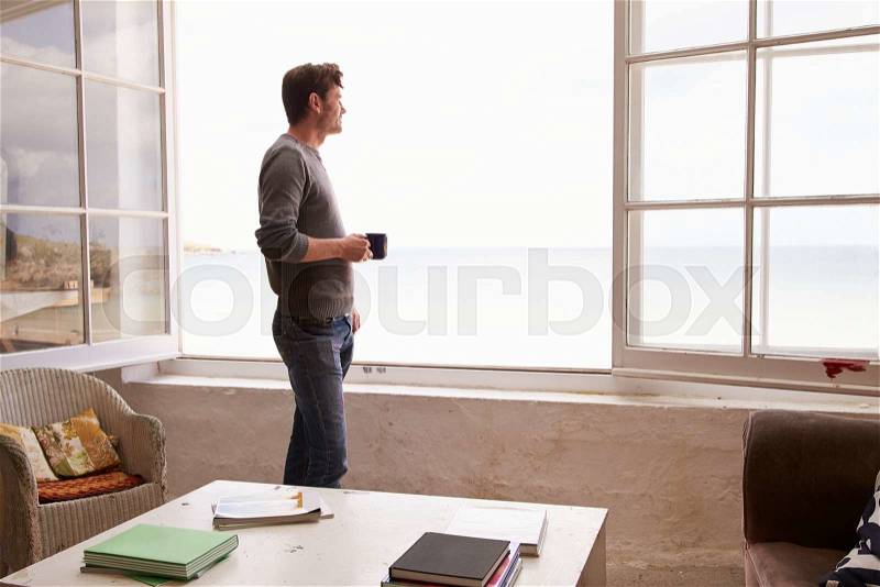Man Standing At Window And Looking At Beautiful Beach View, stock photo