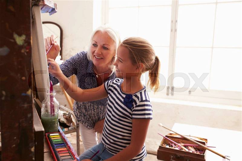 Mother And Daughter Working On Painting In Art Studio, stock photo