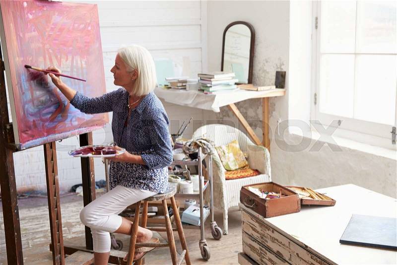 Female Artist Working On Painting In Studio, stock photo