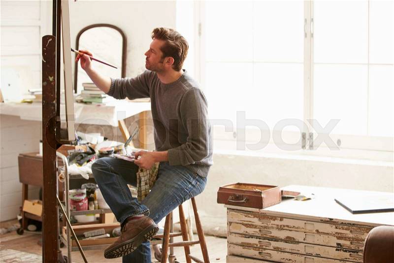 Male Artist Working On Painting In Studio, stock photo