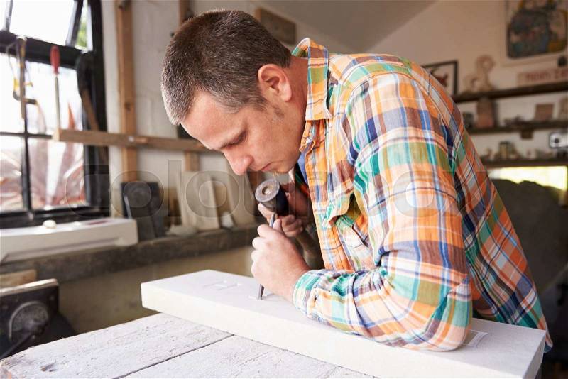 Stone Mason At Work On Carving In Studio, stock photo
