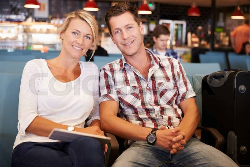 Couple In Airport Departure Lounge Waiting To Go On Vacation, stock photo