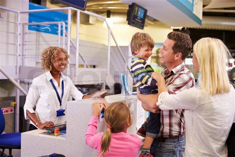 Family At Airport Check In Desk Leaving On Vacation, stock photo