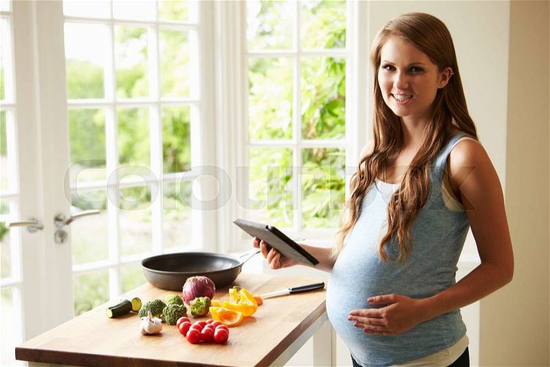 Pregnant Woman Following Recipe On Digital Tablet, stock photo