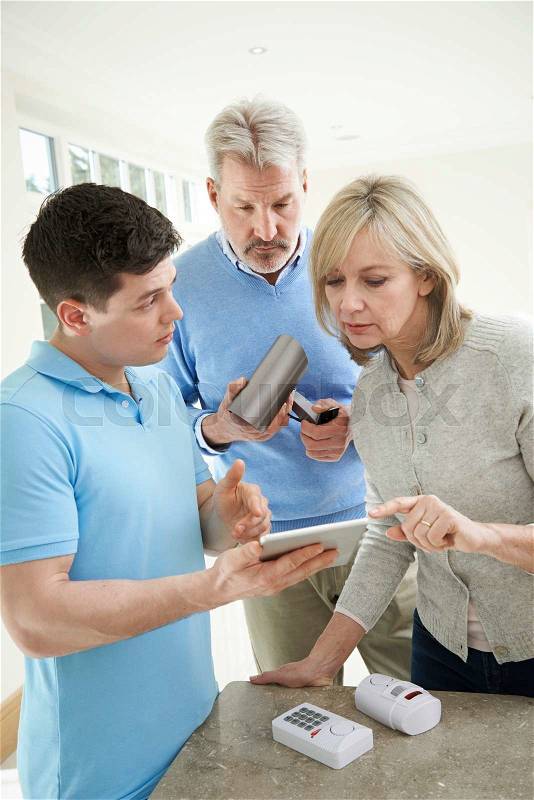 Security Consultant Demonstrating Alarm System To Mature Couple, stock photo
