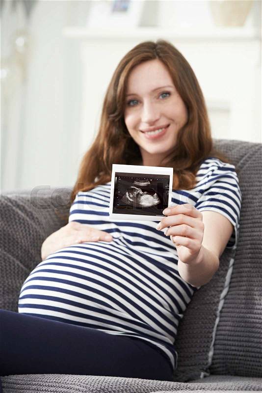 Portrait Of Pregnant Woman Holding Ultrasound Scan Of Baby, stock photo