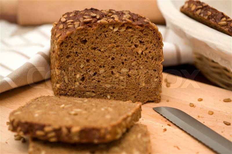 Whole grain bread, knife and towel on plank, shallow depth of field, stock photo