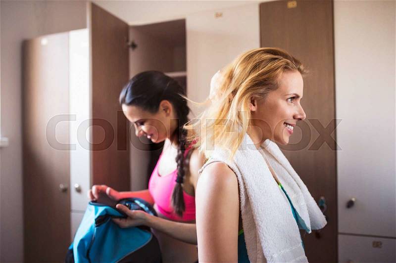 Two attractive fit woman changing in locker room in gym, workout clothes, stock photo