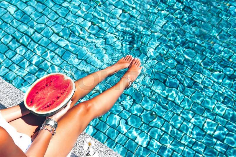 Girl holding watermelon in the blue pool, slim legs, instagram style. Tropical fruit diet. Summer holiday idyllic, stock photo