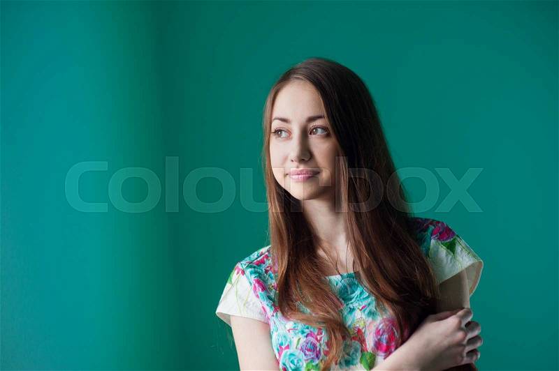 Beautiful young woman standing near a window in the room, stock photo