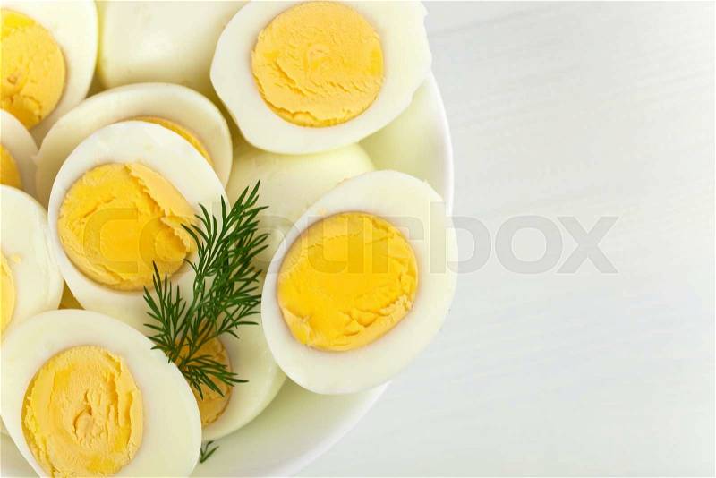 Boiled eggs in a white dish on wooden table, stock photo