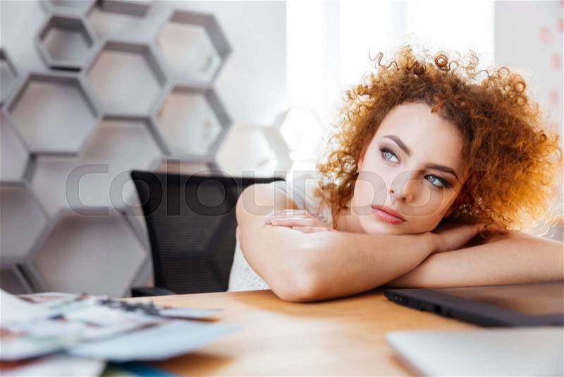 Attractive thoughtful woman designer sitting and dreaming on workplace, stock photo