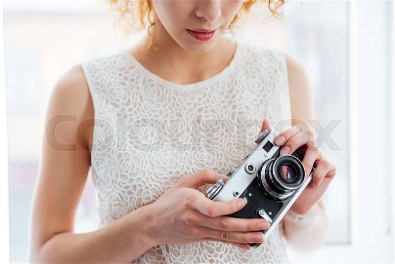 Serious young woman photographer holding vintage camera, stock photo