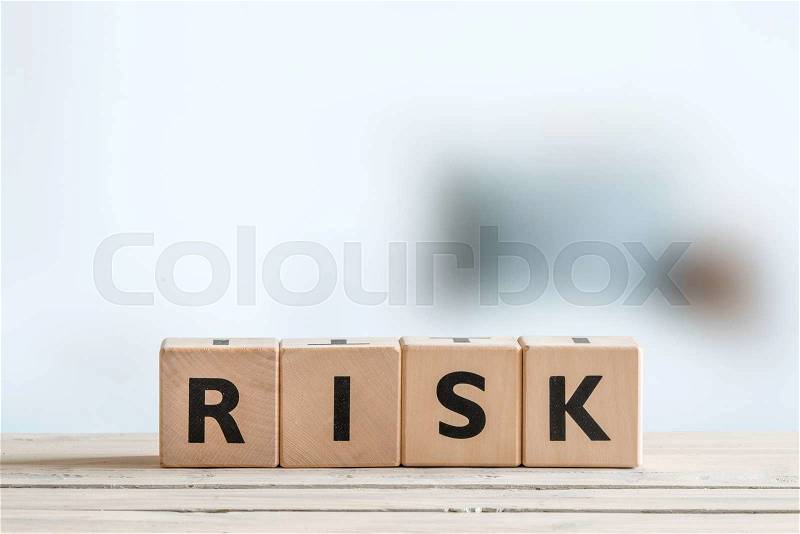 Risk message sign on a wooden office table, stock photo