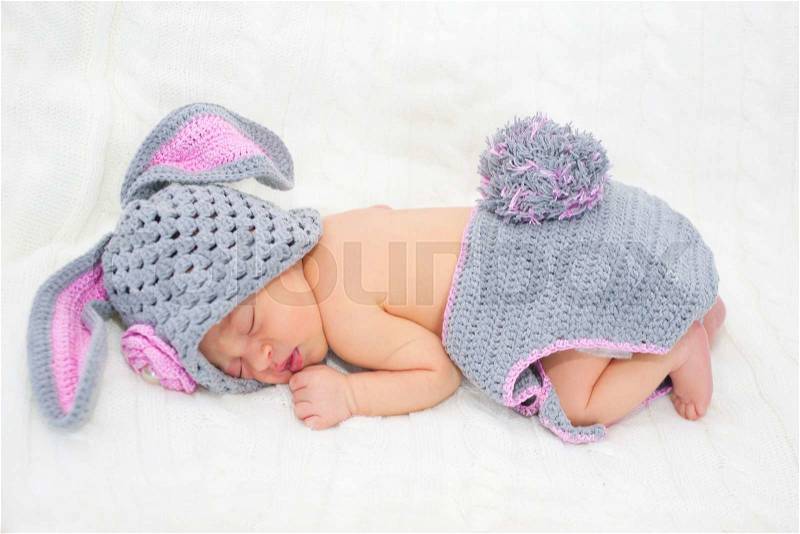 Sleeping newborn baby in Easter rabbit costume on a knitted blanket, stock photo